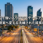 夕暮れ時の名古屋駅周辺のビル群と、手前から奥へと真っ直ぐに伸びる明るい道路。経営戦略の道筋とスケールアップを象徴する洗練された風景。